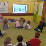 
Dzieci na dywanie oglądają filmy edukacyjny o Wiośnie.