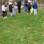 pięciu uczniów na boisku szkolnym zbiera śmiecie do plastikowych worków