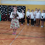 uczennica w stroju Krakowianki w tle chór, żołnierze, uczniowie-drzewa