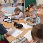 dzieci siedzą przy stoliku i rysują kredkami