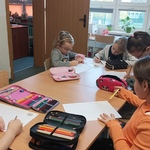 dziewczynki siedzą przy stoliku i rysują kredkami