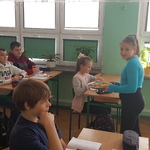 uczennica częstuje upieczonymi ciasteczkami uczniów w pracowni przyrodniczej