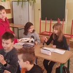 uczniowie klasy 4b jedzą ciasteczka, którymi częstował uczeń klasy 5b