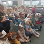 dzieci z przedszkola siedzą na dywanie i krzesełkach i oglądają przedstawienie