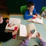 dzieci czytają książkę, trzymają w ręku zakładkę z napisem DKK