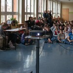 drużyny odpowiadają podnosząc kartki, publiczność obserwuje
