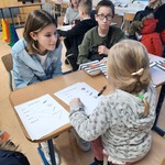 dzieci siedzą przy stolikach, wykonują ćwiczenia na kartce