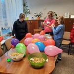 na stole kolorowe balony, makaron w miskach, obok pani i dwie dziewczynki