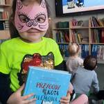 dziewczynka w masce kota trzyma książkę 