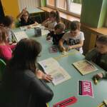 dzieci i pani kierownik  przy stolikach z rozłożonymi książkami