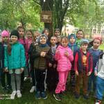 uczniowie klasy 1b stoją przed drzewem na którym powieszony jest domek dla owadów499_8559436543961605710_n.jpg