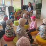 dzieci siedzą na pufach i słuchają pani bibliotekarki