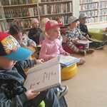 dzieci z książkami siedzą na pufach