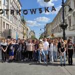 wszyscy uczestnicy wycieczki na ul. Piotrowskiej z  napisem na górze Piotrkowska