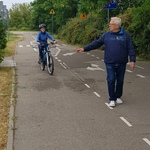 Egzaminator idzie przodem, za nim jedzie na rowerze uczeń