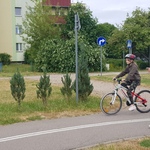 dziewczynka jedzie na rowerze, obok egzaminator idzie, wskazując palcem