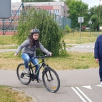 dziewczynka jedzie na rowerze, pokazuje ręką skręt, obok idzie pan