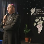 Arcybiskup Józef Guzdek przemawia przez mikrofon, w tle napis Witamy księdza Arcybiskupa