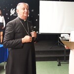 Pani dyrektor wręcza Jego Ekscelencji pamiątkową pocztówkę i obraz