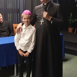 Arcybiskup z uczniem klasy 2. Uczeń ma na głowie piuskę biskupią