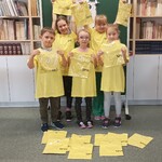 uczniowie ubrani w koszulki, trzymają w ręku zapakowane koszulki