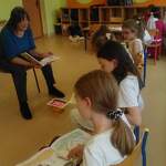 Pani bibliotekarka czyta, dzieci trzymają książki