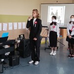 dwaj uczniowie akompaniują śpiewającemy Rotę koledze