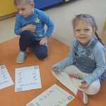 Dzieci na dywanie rozwiązują karty pracy