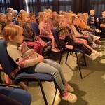 Dzieci siedzą na krześle i słuchają spektaklu.