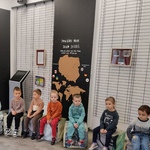  Dzieci siedzą w kole i słuchają opowieści o woskowych zwierzętach