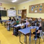 Policjantka omawia zasady bezpiecznego poruszania się po drodze a dzieci słuchają zaciekawione
