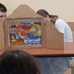 Uczniowie klasy 7 A przedstawiają historię smoka w formie teatrzyku kamishibai