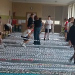 Wolontariusze rozkładają papierowy łańcuch na korytarzu szkolnym