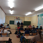 Uczniowie klasy 7 b siedzą w ławkach. Dzielnicowi informowali uczniów o konsekwencjach cyberprzemocy
