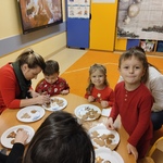 Dzieci w raz z rodzicami dekorują pierniki przy stoliku
