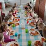 Dzieci z grupy Pszczółki przy stole jedzą pizzę