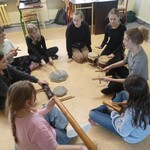 Uczennice z nauczycielką muzyki grają na instrumentach perkusyjnych