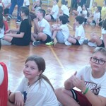 Uczniowie siedzą w rzędach przygotowani do konkurencji sportowych 