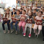 Dzieci z klasy I B prezentują książkę, którą otrzymały po pasowaniu