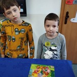 Dwóch chłopców stoi przy ułożonym obrazku z puzzli