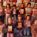 Dziewczynki z klasy I B prezentują swoje pierwsze książki wypożyczone w bibliotece szkolnej