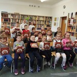 Dzieci z klasy I A prezentują książkę, którą otrzymały po pasowaniu
