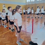 Dzieci na sali gimnastycznej stoją w rzędach podczas zawodów sportowych