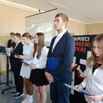 Uczniowie z klasy 7 A recytują wiersze w tle prezentacja multimedialna