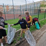 Uczniowie klasy siódmej zbierają śmieci w otoczeniu szkoły