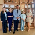 Goście z Urzędu Miejskiego i kuratorium w towarzystwie pani dyrektor na tle gabloty z pucharami
