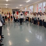 Uczniowie klas 4 - 8 na korytarzu szkolnym przygotowani do apelu