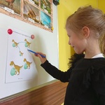 
 Dziewczynka przy tablicy łączy dinozaury
